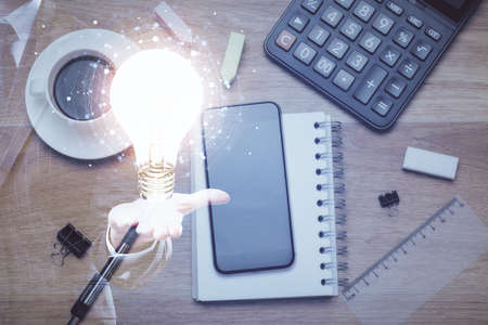 Double exposure of bulb drawing over table with phone. Top view. Concept of idea.の写真素材