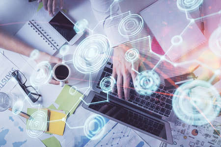 Double exposure of man's hands typing over computer keyboard and social network theme hologram...