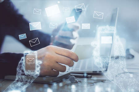 Double exposure of man's hands holding and using a digital device and envelop hologram drawing. E-mail concept.の写真素材