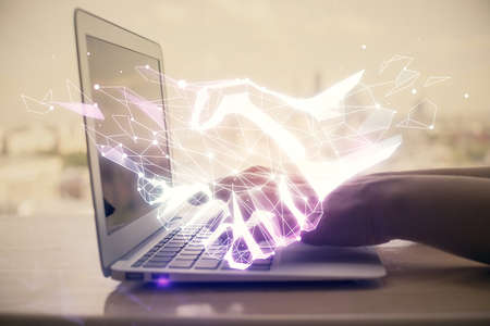 Double exposure of woman hands typing on computer and handshake drawing. Partnership concept.の写真素材
