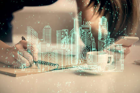 Double exposure of buildings hologram and woman holding and using a mobile device. Smart city concept.の写真素材