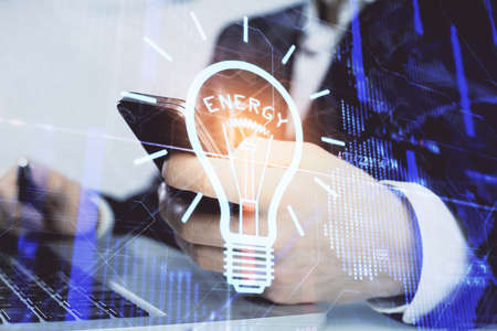Double exposure of man's hands holding and using a digital device and bulb hologram drawing. Idea concept.の写真素材