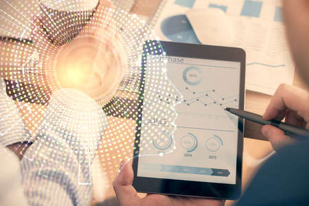 Double exposure of man's hand holding and using a digital device and brain hologram drawing. Data...