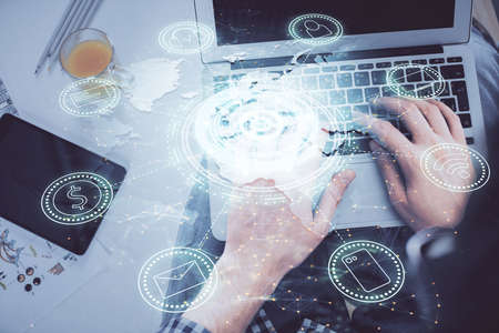 Double exposure of man's hands typing over computer keyboard and social network theme hologram...