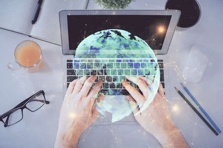 Double exposure of man's hands typing over computer keyboard and social network theme hologram...