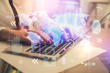 Double exposure of woman hands working on computer and world map hologram drawing. International...