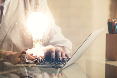 Double exposure of woman hands typing on computer and light bulb drawing. Idea concept.