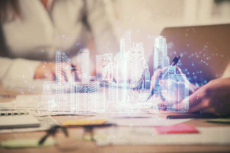 Double exposure of woman hands typing on computer and buildings drawing. Smart-city concept.