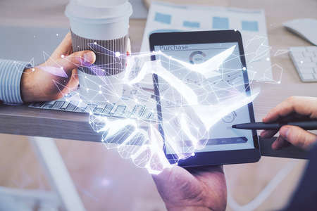Double exposure of man's hands holding and using a digital device and handshake drawing. Partnership...