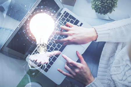Double exposure of woman hands working on computer and light bulb hologram drawing. Top View. Idea concept.の写真素材