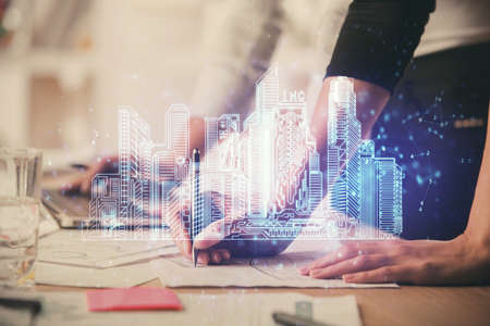 Double exposure of woman hands typing on computer and buildings drawing. Smart-city concept.の写真素材
