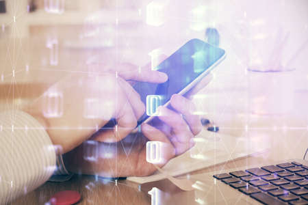 Double exposure of man's hand holding and using a digital device and data theme hologram drawing. Technology concept.の写真素材