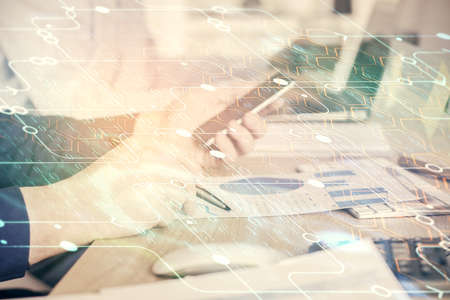 Double exposure of man's hand holding and using a digital device and data theme hologram drawing....