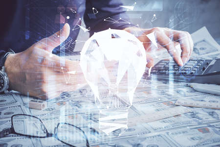 Double exposure of man's hands holding and using a digital device and bulb hologram drawing. Idea...