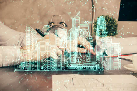 Double exposure of man's hands holding and using a digital device and city drawing.