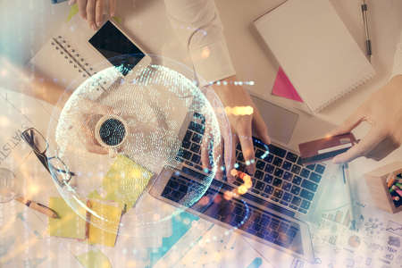 Multi exposure of man's hands typing over computer keyboard and world map hologram drawing. Top view. Technology concept.の写真素材