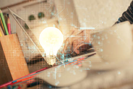 Double exposure of woman hands typing on computer and light bulb drawing. Idea concept.