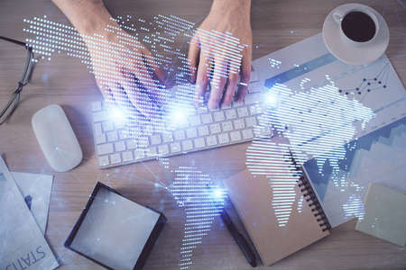 Double exposure of man's hands typing over computer keyboard and social network theme hologram...