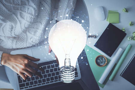 Double exposure of woman hands working on computer and light bulb hologram drawing. Top View. Idea concept.の写真素材