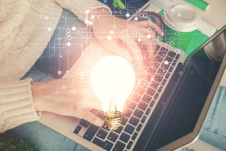 Double exposure of woman hands typing on computer and light bulb drawing. Idea concept.