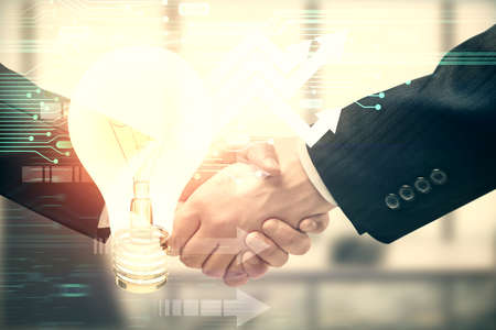 Double exposure of light bulb hologram and handshake of two men. Idea concept.