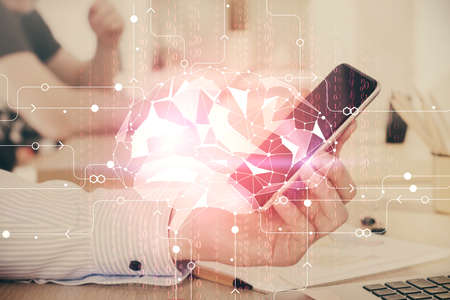 Double exposure of man's hand holding and using a digital device and brain hologram drawing. Data...