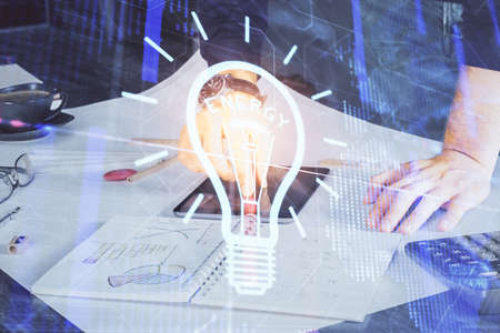 Double exposure of man's hands holding and using a digital device and bulb hologram drawing. Idea concept.の写真素材