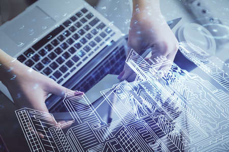 Double exposure of woman hands typing on computer and buildings drawing. Smart-city concept.