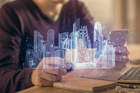 Double exposure of man's hands holding and using a digital device and city drawing.の写真素材