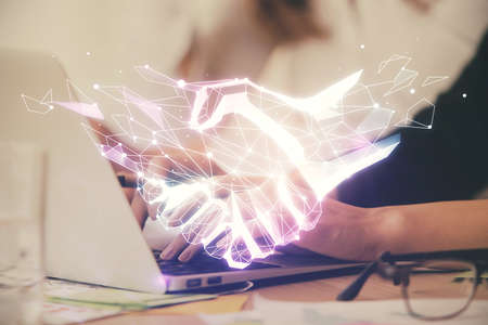 Double exposure of woman hands typing on computer and handshake drawing. Partnership concept.の写真素材