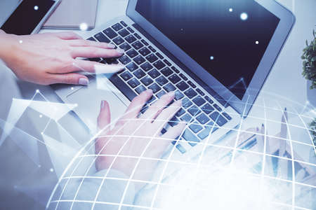 Double exposure of woman hands working on computer and world map hologram drawing. International...