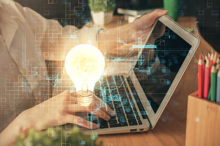Double exposure of woman hands typing on computer and light bulb drawing. Idea concept.