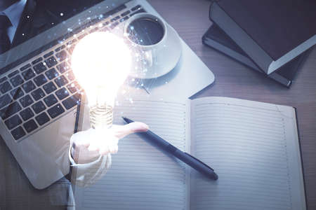 Bulb drawing over computer on the desktop background. Top view. Double exposure. Idea concept.