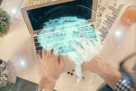 Double exposure of man's hands typing over computer keyboard and brain hologram drawing. Top view....
