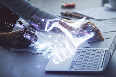 Double exposure of woman hands typing on computer and handshake drawing. Partnership concept.
