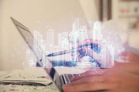 Double exposure of woman hands typing on computer and buildings drawing. Smart-city concept.
