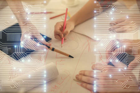 Double exposure of tech theme hologram and man and woman working together holding and using a mobile device.の写真素材