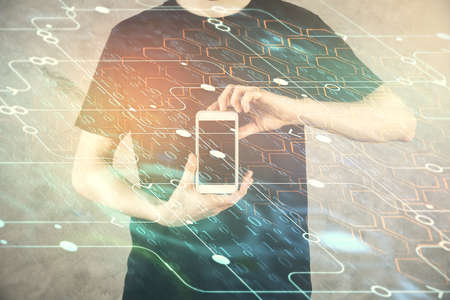 Double exposure of man's hand holding and using a digital device and data theme hologram drawing. Technology concept.の写真素材