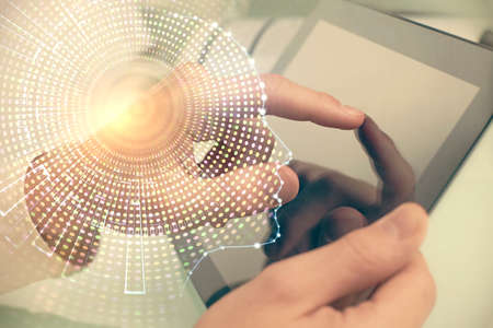 Double exposure of man's hand holding and using a digital device and brain hologram drawing. Data...