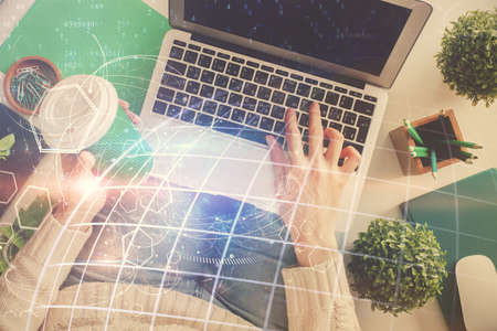 Double exposure of woman hands working on computer and world map hologram drawing. Top View....
