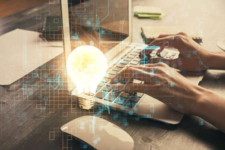 Double exposure of woman hands typing on computer and light bulb drawing. Idea concept.の写真素材