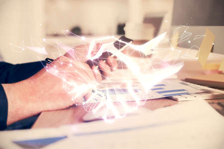 Double exposure of man's hands holding and using a digital device and handshake drawing. Partnership concept.の写真素材