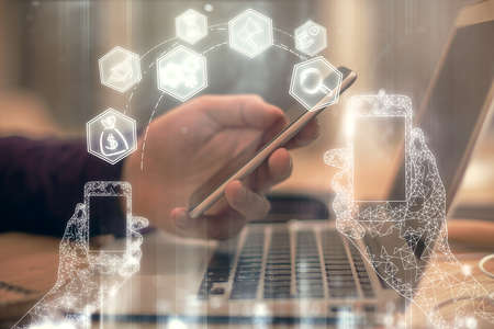Double exposure of man's hands holding and using a digital device and tech theme hologram drawing. Technology concept.の写真素材
