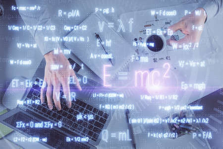 Double exposure of man's hands typing over computer keyboard and formula hologram drawing. Top view....