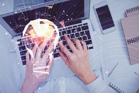 Double exposure of woman hands working on computer and light bulb hologram drawing. Top View. Idea...
