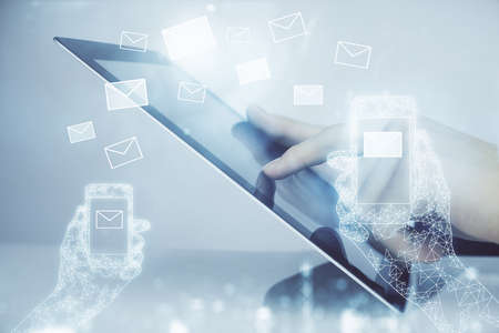 Double exposure of man's hands holding and using a digital device and envelop hologram drawing....