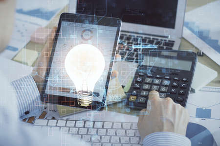 Double exposure of man's hands holding and using a digital device and bulb hologram drawing. Idea concept.の写真素材