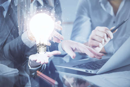 Double exposure of man and woman working together and light bulb hologram drawing. Idea concept....