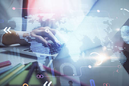 Double exposure of woman hands working on computer and world map hologram drawing. International...