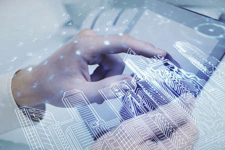 Double exposure of man's hands holding and using a digital device and city drawing.